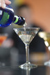 Close up of a hand pouring cocktail in a glass.