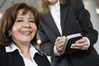 Photo: Portrait of a business woman smiling and other holding a pda. Portrait of a business woman smiling and other holding a pda.