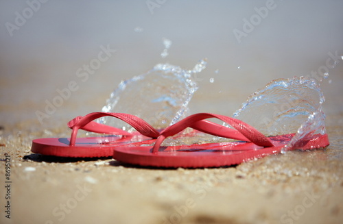 Photo: Flip flops on the beach with water splashing Flip flops on the beach with water splashing