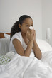 Girl 7-9 blowing nose in bed