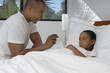 Male nurse taking temperature of girl 7-9 lying in bed