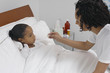 Nurse taking temperature of girl 7-9 lying in bed