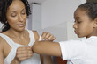Mother applying bandaid to daughter 7-9 indoors