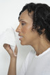 Woman holding tissue to face, studio shot