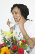 Woman with allergy holding tissue, near flowers, studio shot
