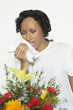 Woman with allergy holding tissue, near flowers, studio shot
