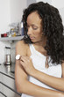 Woman applying patch to arm, indoors