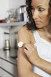 Woman applying patch to arm, indoors, close-up