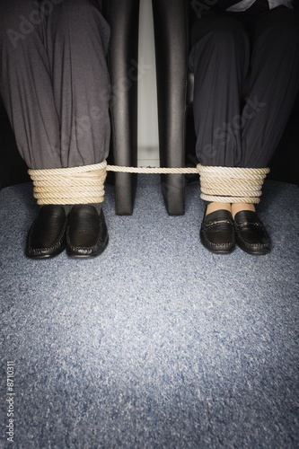 Photo: Male and female business people's legs tied Male and female business people's legs tied