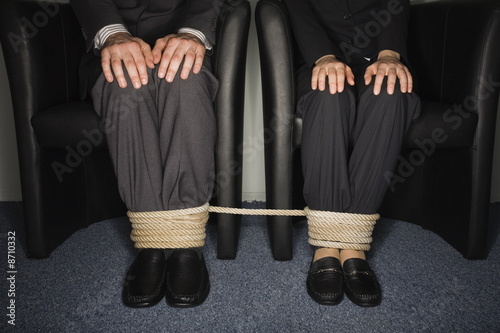 Photo: Male and female business people's legs tied Male and female business people's legs tied