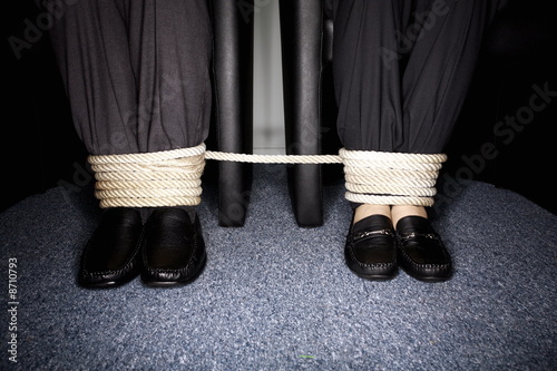Photo: Male and female business people's legs tied Male and female business people's legs tied