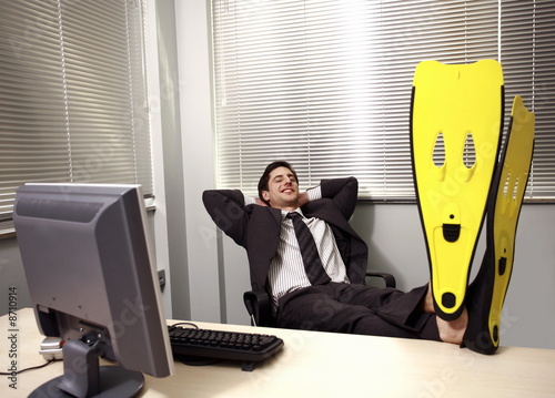 Photo: Office worker at computer wearing swim flippers Office worker at computer wearing swim flippers