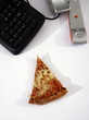 Slice of pizza next to phone on office desk