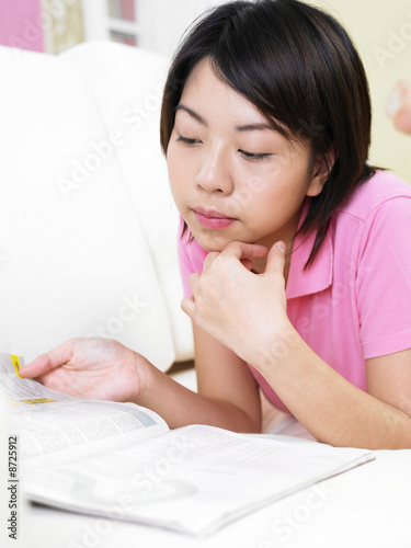 Photo: A woman readign a book while resting on the sofa A woman readign a book while resting on the sofa