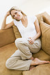 Woman in living room listening to MP3 player smiling Woman in living room listening to MP3 player smiling