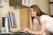 Photo: Woman in kitchen with computer smiling Woman in kitchen with computer smiling