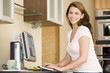 Photo: Woman in kitchen with computer smiling Woman in kitchen with computer smiling