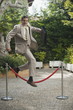 Businessman in garden jumping over barrier