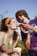 Male teenager feeding female teenager pizza