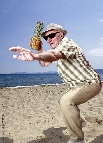 Photo: Male senior with pineapple on the beach Male senior with pineapple on the beach