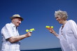 Senior couple on beach with water guns