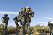 Soldiers walking in field, one carrying colleague