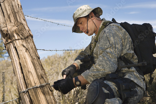 Photo: Soldier cutting barbed wire fence Soldier cutting barbed wire fence