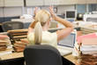 Photo: Businesswoman in cubicle with laptop and stacks of files Businesswoman in cubicle with laptop and stacks of files