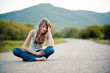 Tired young girl sitting down on road Tired young girl sitting down on road