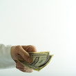 studio close up of hand giving dollar bills