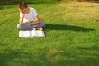 Young boy outdoors on the grass reading a book