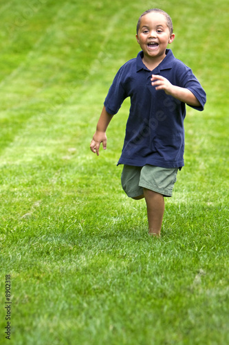 Photo: Happy mixed race boy running through green grass Happy mixed race boy running through green grass