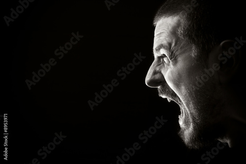 Photo: Portrait of screaming angry man on black background Portrait of screaming angry man on black background