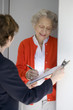 Attractive senior woman signing a document at her front door