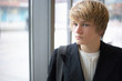 Teenage boy near window in urban building, interior