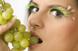 close up of a sensual girl with green eyelashes and grape