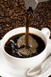 Pouring coffee into a white cup with beans in the background