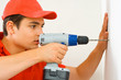 A mand drilling a hole in the wall.