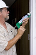 Elderly contractor caulking around glass door frame Elderly contractor caulking around glass door frame
