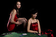 Two woman playing poker at a table with red cabaret dresses Two woman playing poker at a table with red cabaret dresses