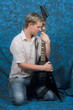 A young guitar player on a blue background holding the guitar