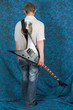 A young guitar player's back on a blue background