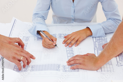 Closeup of female architect's hands making blueprints