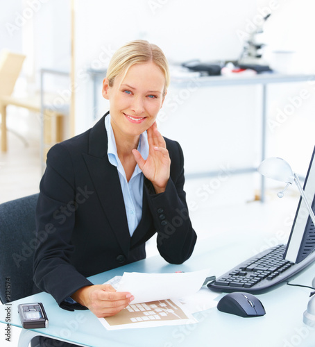 Photo: Portrait of a young smiling business woman sitting at office Portrait of a young smiling business woman sitting at office