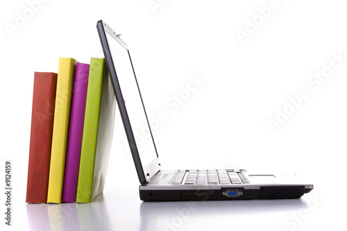 Photo: a laptop next to a stack of colorful books a laptop next to a stack of colorful books