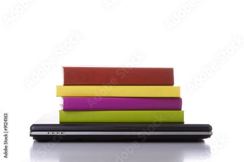 a laptop next to a stack of colorful books