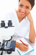 female researcher sitting at a laboratory and writing notes