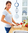 Happy woman standing and cutting apple in the kitchen