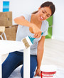 Smiling teenage girl painting white color to a table