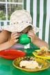Little girl in big hat eats sweets and drinks tea